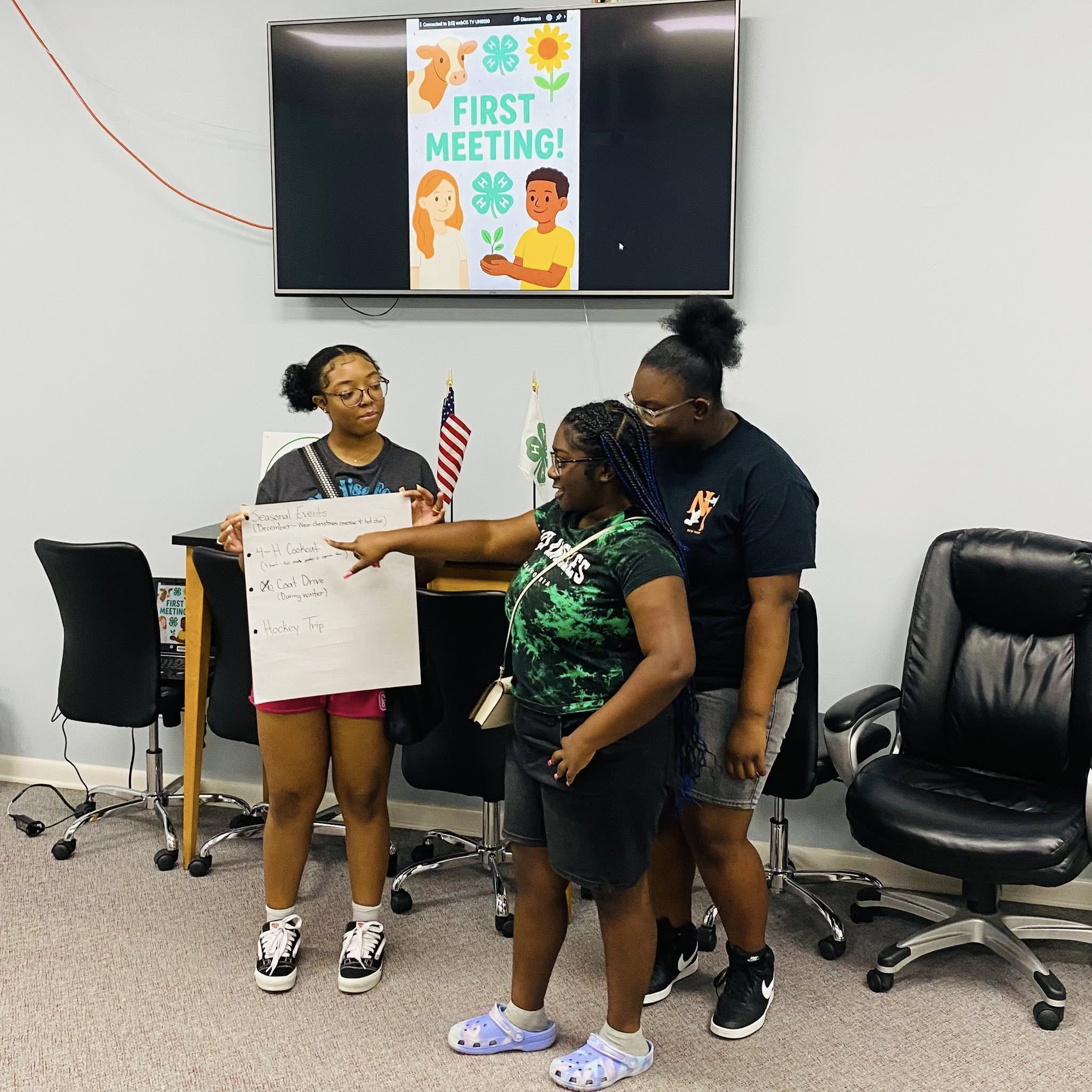 A girl holding a poster while two others are looking at it.